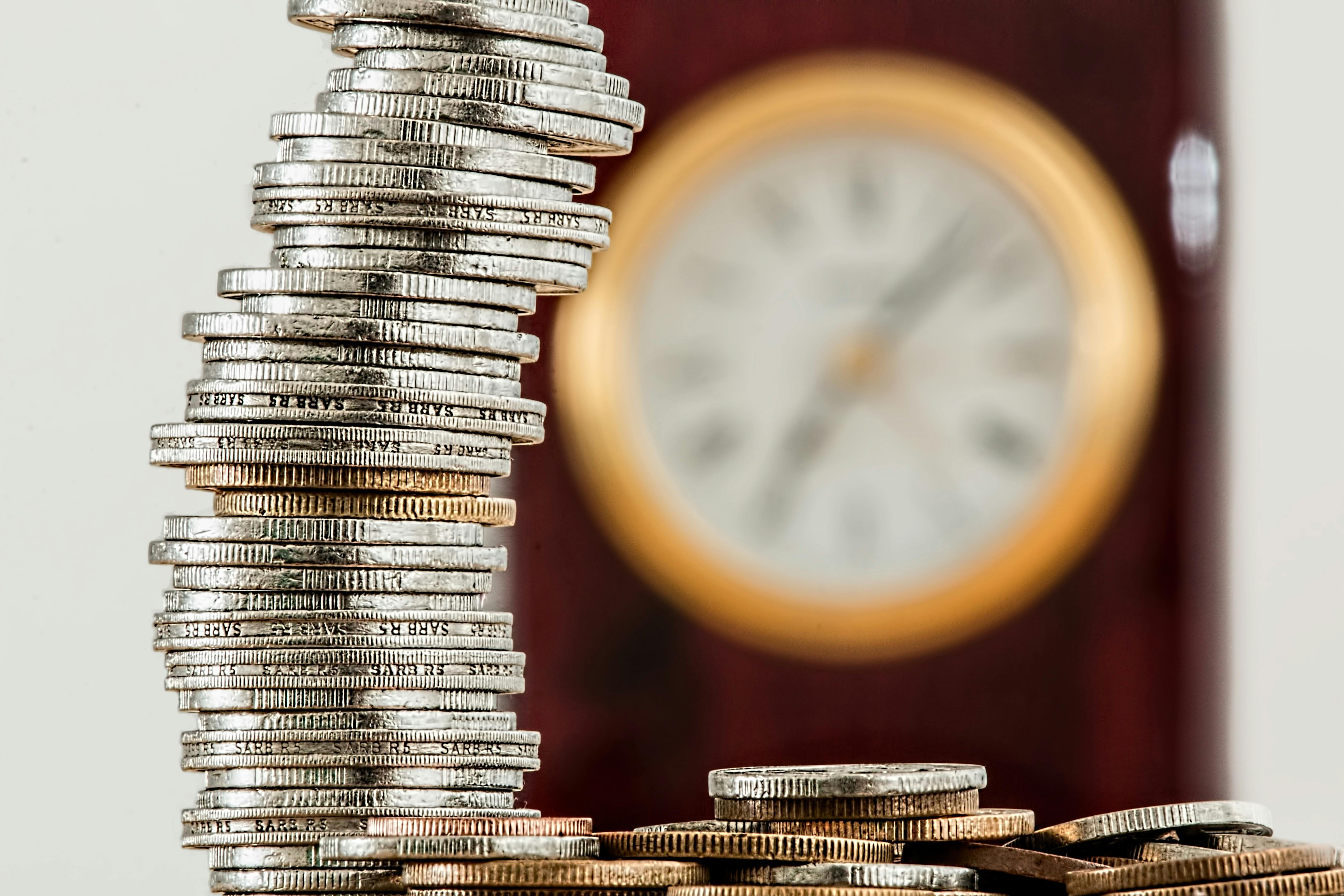 Stacked coins beside a clock representing study planning and costs